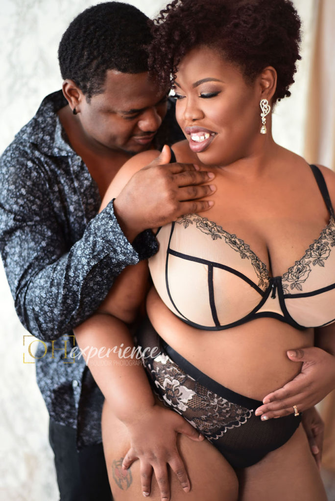 Black couples with woman in bra and panty set. Guy has on button down shirt and black pants. His hand is on her collarbone