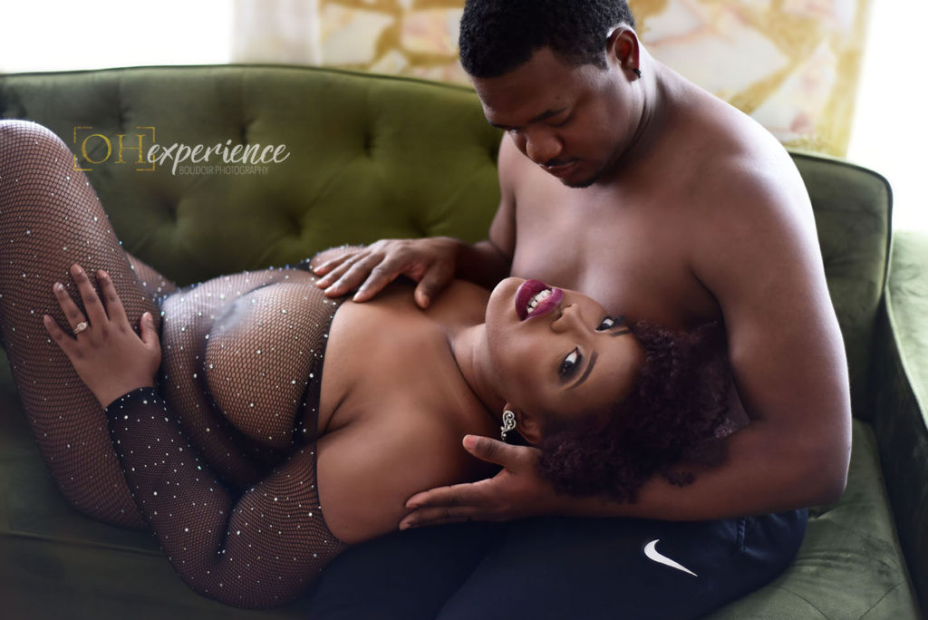 black woman in rhinestone body suit laying with her head on her husbands lap. He is gazing down at her. She is looking at the camera. couples boudoir experience 