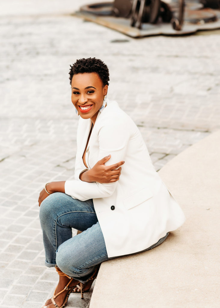 black-woman-in-white-blazer-and-jeans-sitting-on-stone-steps