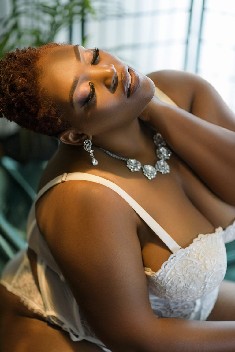 Black woman with short natural hair in white lingeire on a emerald satin sheet, Maryland black boudoir photographer