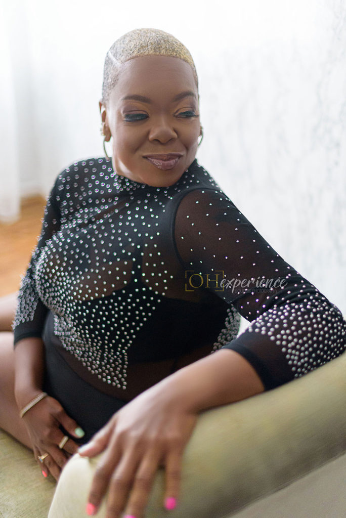 black woman sitting on green couch in black sparkle bodysuit
