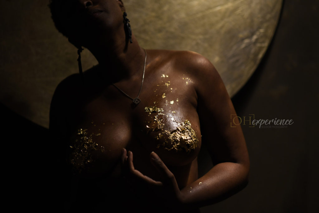 Black woman with gold leaf on her body and large earrings