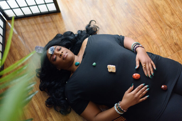 Johari & Lou Black woman laying on her back with chakra crystals on her body