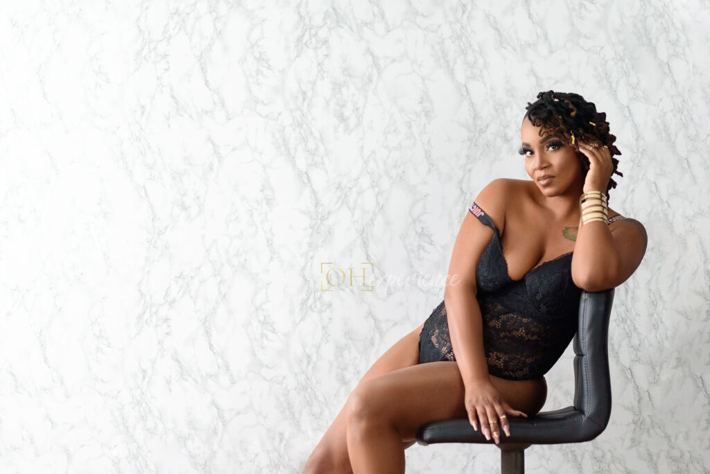 Black Woman in black lace lingerie sitting on a stool. 