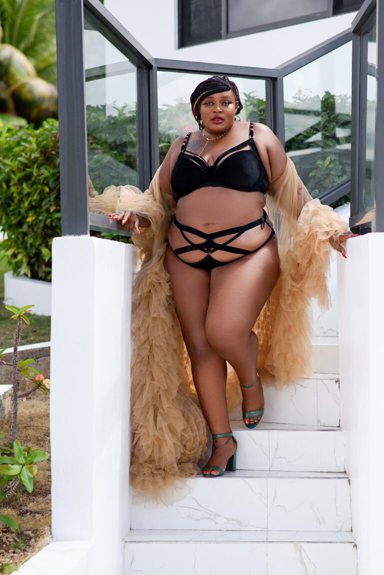 BLACK WOMEN IN SAND COLOR TULLE ROBE WALKING DOWN WHITE STEPS IN BLACK STRAPPY LINGERIE