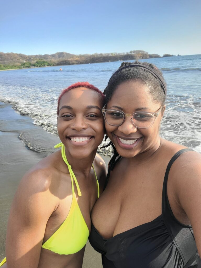 Black women posing in front of the ocean