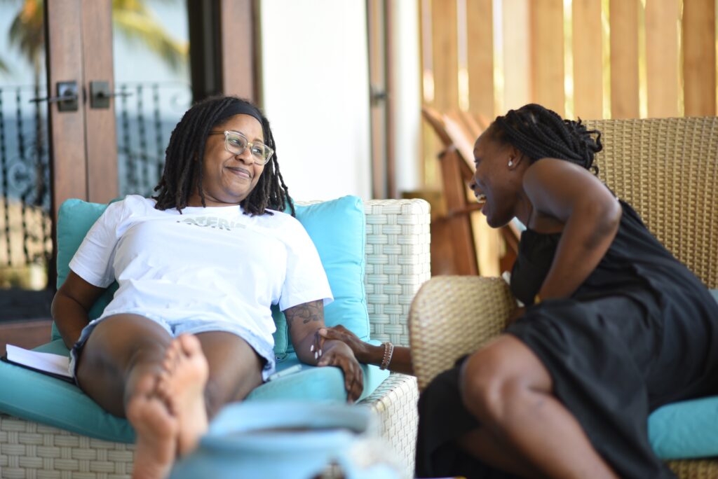 Black women laughing together sitting on lounge furniture