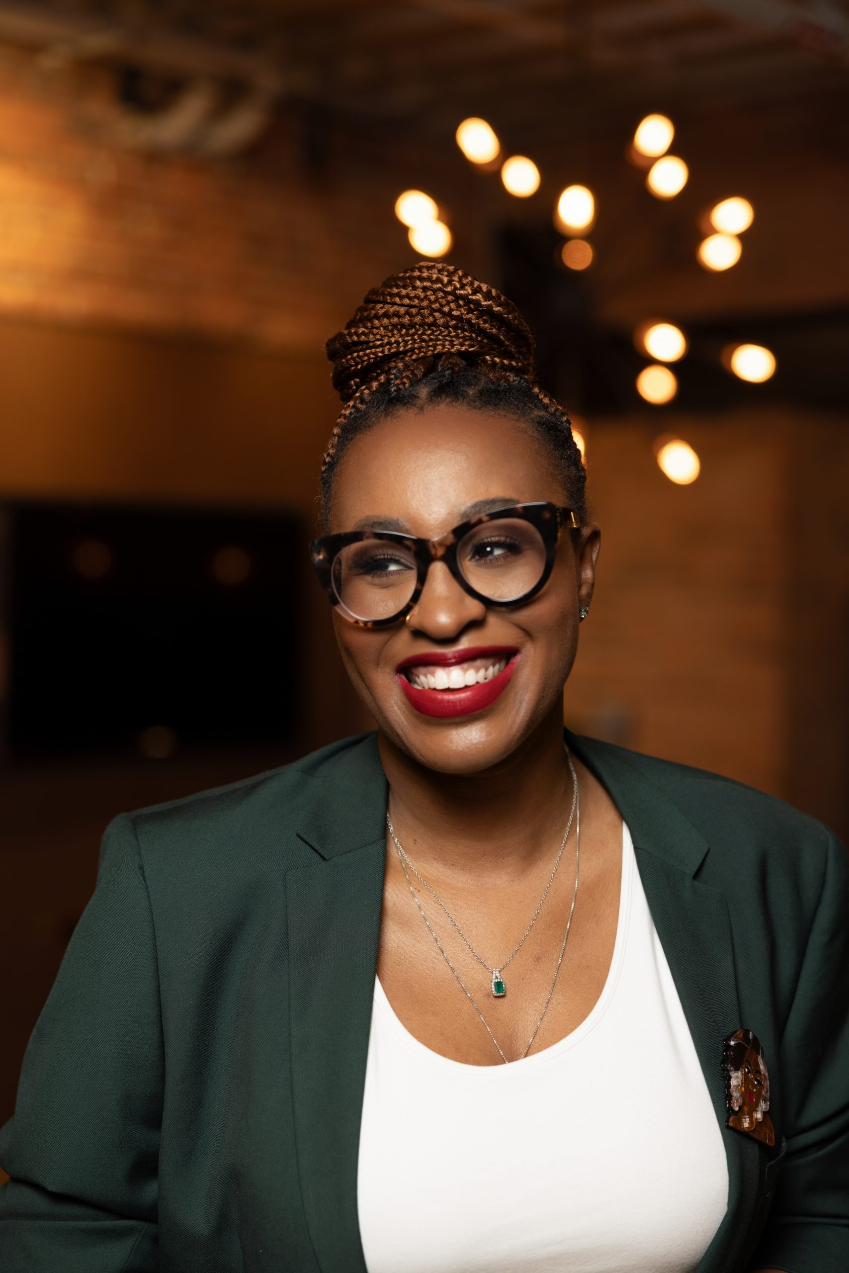 Black woman with braided bun in hunter green blazer